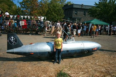 August in front of rocket car